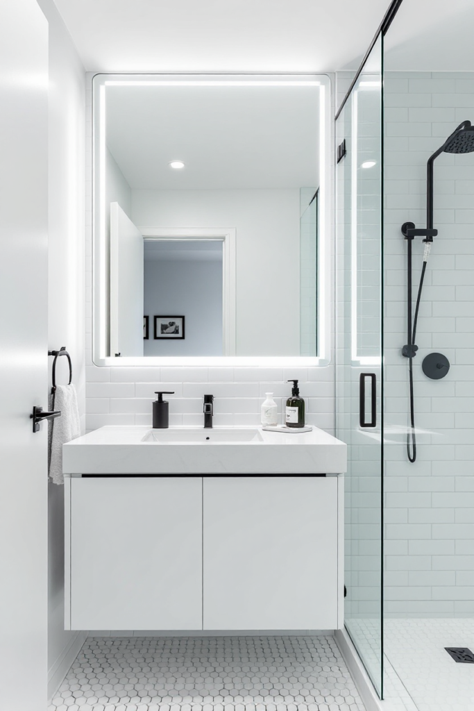 10 Brilliant Small Bathroom Decor Ideas for a Stylish & Spacious Look 17 Small bathroom decor with a floating white vanity, LED-lit mirror, glass-enclosed shower, black fixtures, and hexagonal floor tiles for a sleek, modern look.