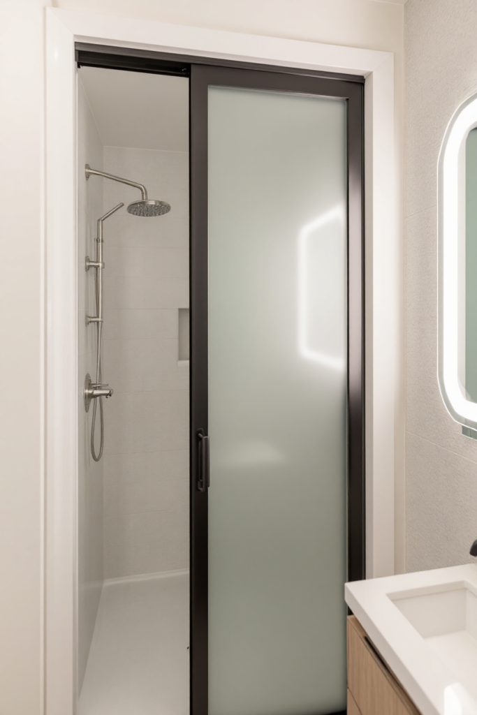 10 Brilliant Small Bathroom Decor Ideas for a Stylish & Spacious Look 19 Small bathroom decor with a frosted glass sliding door, rainfall shower, built-in niche, modern vanity, and LED-lit mirror for a sleek, minimalist look.