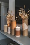 DIY Ideas with Cardboard Tubes: 20+ Astonishing Decor Hacks DIY Ideas with Cardboard Tubes : candle holders and vases made from cardboard tubes, wrapped in earthy-toned fabric, create a warm and rustic display on a shelf.