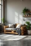 Sunlit living space with gray cushions and throw on a wooden DIY Pallet Sofas setup, surrounded by potted plants.