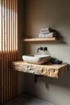 Japandi bathroom with a raw-edge wood vanity, stone vessel sink, matte black fixtures, and soft lighting for a natural, minimalist look.
