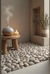 Scandinavian Bathroom: 15 Amazing Ideas for a Calm Space Zen bathroom corner with smooth river stones, a wooden stool holding a ceramic diffuser and candle, and a recessed shelf with greenery.