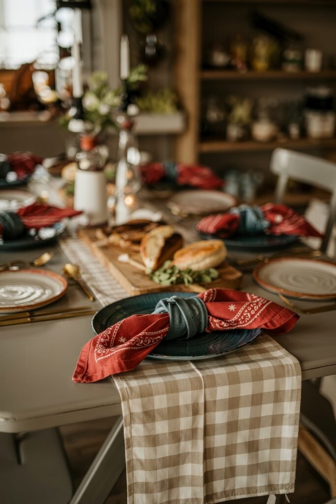 Patriotic 4th of July Table Décor & Centerpieces 5 Casual holiday dining table with beige gingham runner, red bandana napkins, and fresh bread for a laid-back 4th of July gathering.