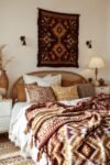 Bed with tribal throw blankets, textured pillows, and warm boho bedroom color palette decor