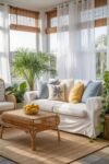 Cozy Fall Sunroom Ideas: Autumn Decor for a Warm Retreat Bright summer sunroom with a white sofa, blue and yellow pillows, rattan coffee table, and lush green plants creating a breezy, inviting atmosphere.