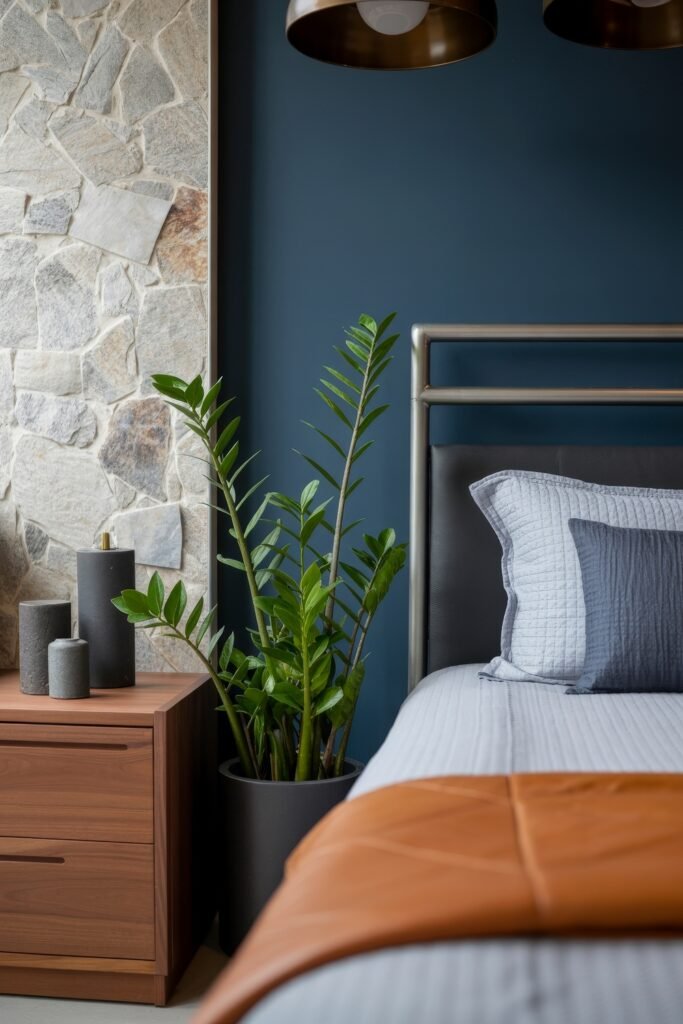 Masculine Luxury Bedroom: Genius Luxe Ideas 30 Modern bedroom corner with a dark blue wall, light stone accent, and a metal-frame bed, complemented by a ZZ plant in a black pot beside a wood nightstand with minimalist decor.