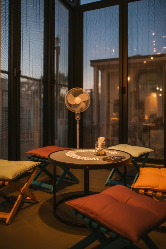Bright Summer Sunroom Ideas: Airy Decor for Sunny Days 29 An intimate four-season room with a round table, colorful cushioned chairs, and playing cards set up for an evening game.