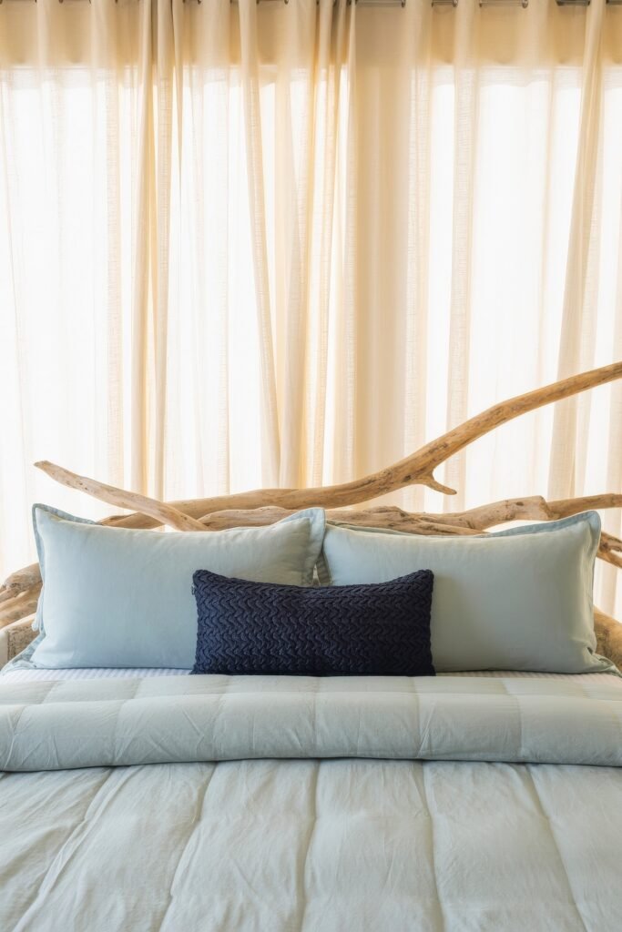 Coastal Summer Vibes for City Apartments 6 Cozy bedroom with light blue pillows and a navy accent pillow against a driftwood headboard, adding a subtle summer décor touch.