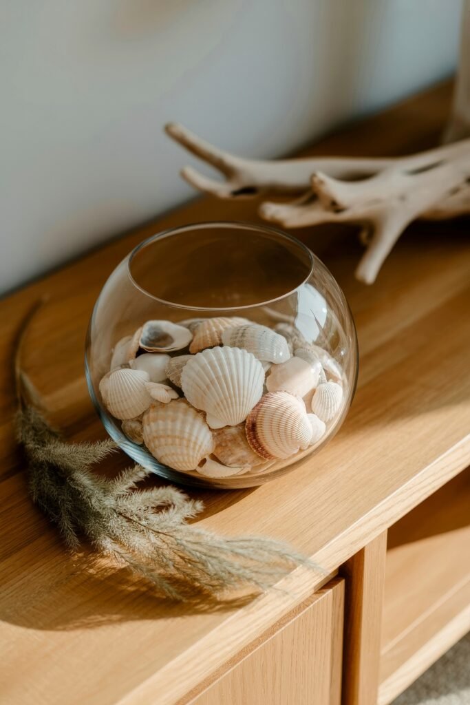Coastal Summer Vibes for City Apartments 21 Glass bowl filled with seashells on a wooden console, adding a beachy summer décor detail.