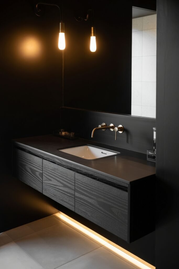 Black Bathroom Ideas: Genius Ways to Create Moody Glam 18 Floating black vanity with underlighting and wall-mounted brass faucet, contrasted by light floor tiles, creating a sleek, ambient Dark & Moody Bathroom Theme.
