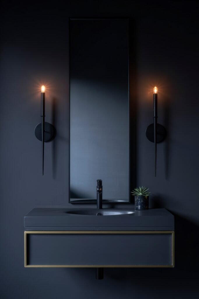 Gothic Bathroom Ideas: Genius Touches for Moody Glam 26 Minimalist black bathroom featuring a rectangular mirror, slim sconces, and floating vanity with brass trim, expressing modern elegance in a Dark & Moody Bathroom Theme.