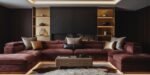 Luxury Sofa Living Room: Furniture for a Luxury Lounge Contemporary luxury living room with a deep burgundy velvet sectional sofa accented by metallic and neutral throw pillows, set against a dark marble fireplace with gold-lit shelving and a textured rug.