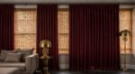 Luxury Curtains Living Room: Luxurious Curtains & Window Treatments Sophisticated luxury living room featuring rich burgundy curtains over bamboo shades, a grey sectional sofa, and vintage-style brass lamps on black tile flooring.