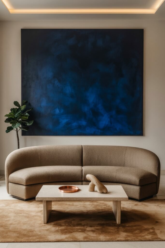 Modern Luxury Living Room: Designing a Sleek Luxe Lounge 12 Contemporary luxury living room showcasing a taupe curved sofa, travertine coffee table, copper tray and towering deep blue abstract painting framed by a fiddle-leaf fig