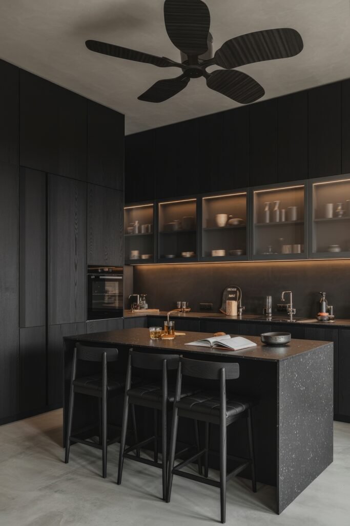 Chic Ways to Style a Modern Black Kitchen 20 Minimalist modern black kitchen with flat cabinetry, matte black finishes, an island with a speckled countertop, and under-cabinet lighting creating a sleek, cohesive space.