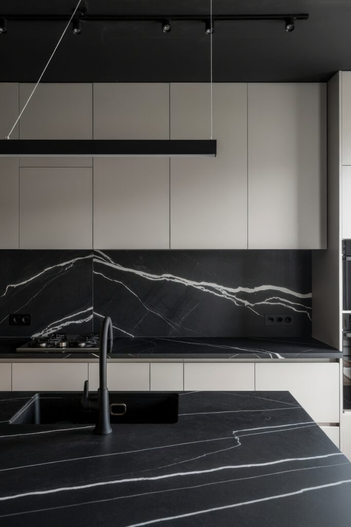 Inspiring Styles to Refresh Your White Kitchen Cabinets 22 Modern minimalist kitchen with matte beige cabinets and dramatic black marble countertops and backsplash accented by clean lines and bold lighting.
