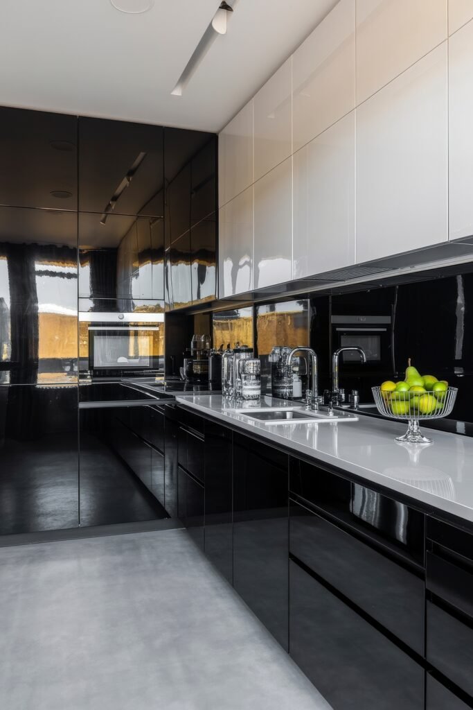 Stunning Ways to Style Black Kitchen Cabinets 31 Ultra-modern kitchen with high-gloss black kitchen cabinets, reflective surfaces, and sleek white countertops, featuring built-in appliances, chrome fixtures, and a bowl of green apples adding a pop of color.