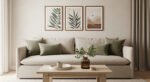 Neutral living room with a beige sofa, green throw pillows, wooden coffee table with a vase of greenery, and three framed botanical prints above, creating a soft aesthetic apartment decor.