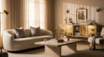 Neutral-toned living room with a curved cream sofa, minimalist wooden coffee table, and illuminated sideboard, styled with abstract art and soft natural light for a luxury apartment aesthetic.