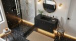 Black and Gold Bathroom Decor Ideas for Luxe Everyday Calm Modern bathroom with terrazzo floors, black vanity with gold fixtures, round mirror, and glass shower enclosure illuminated with soft under-cabinet lighting, offering Bathroom Decor Inspo.