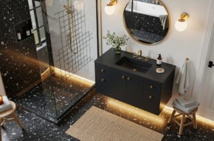 Modern bathroom with terrazzo floors, black vanity with gold fixtures, round mirror, and glass shower enclosure illuminated with soft under-cabinet lighting, offering Bathroom Decor Inspo.