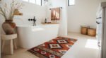 Desert-Modern Magic: Western Bathroom Decor Ideas Bright bathroom with a freestanding white tub, terracotta vase of dried grasses, patterned southwestern rug, woven baskets, and warm neutral accents for Bathroom Decor Inspo.
