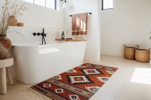 Bright bathroom with a freestanding white tub, terracotta vase of dried grasses, patterned southwestern rug, woven baskets, and warm neutral accents for Bathroom Decor Inspo.