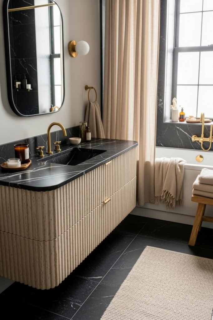 Black and Gold Bathroom Decor Ideas for Luxe Everyday Calm 6 Elegant space with a ribbed wood vanity, black marble countertop, gold faucet, and bathtub by a large window, styled with soft beige towels and candles.