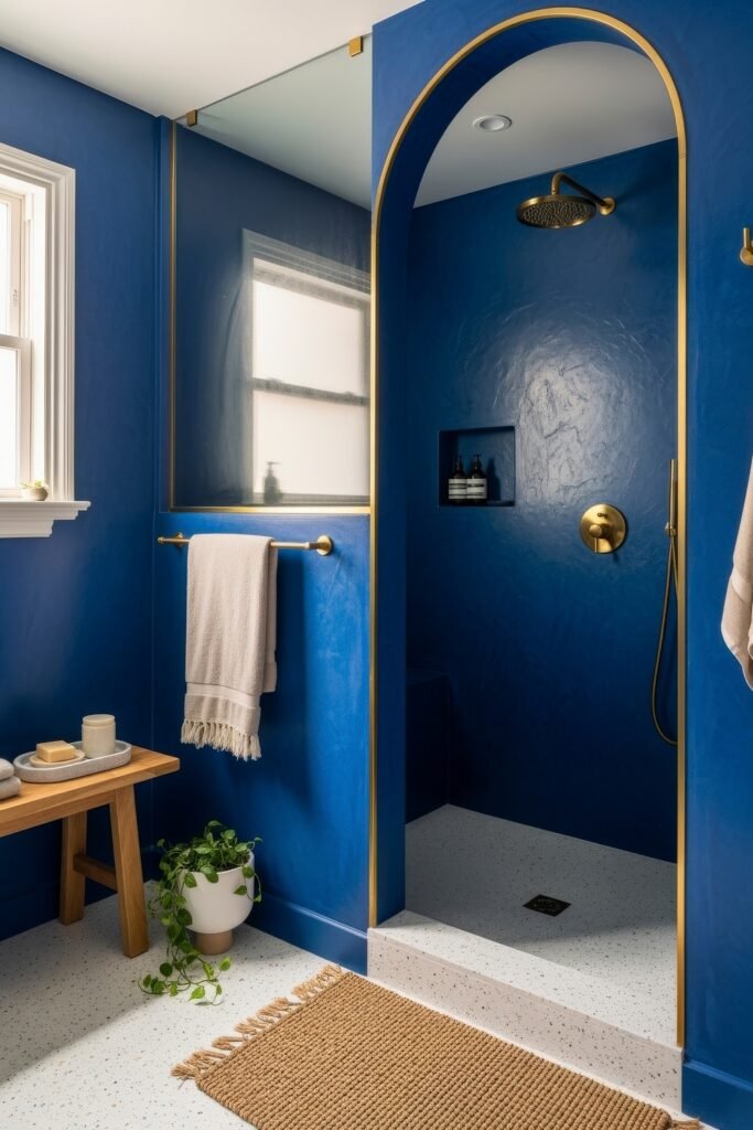 Blue Bathroom Decor: Fresh, Wow-Worthy Ideas 7 Bold bathroom with deep blue walls, gold accents, and an arched shower entry enhancing modern blue bathroom decor.