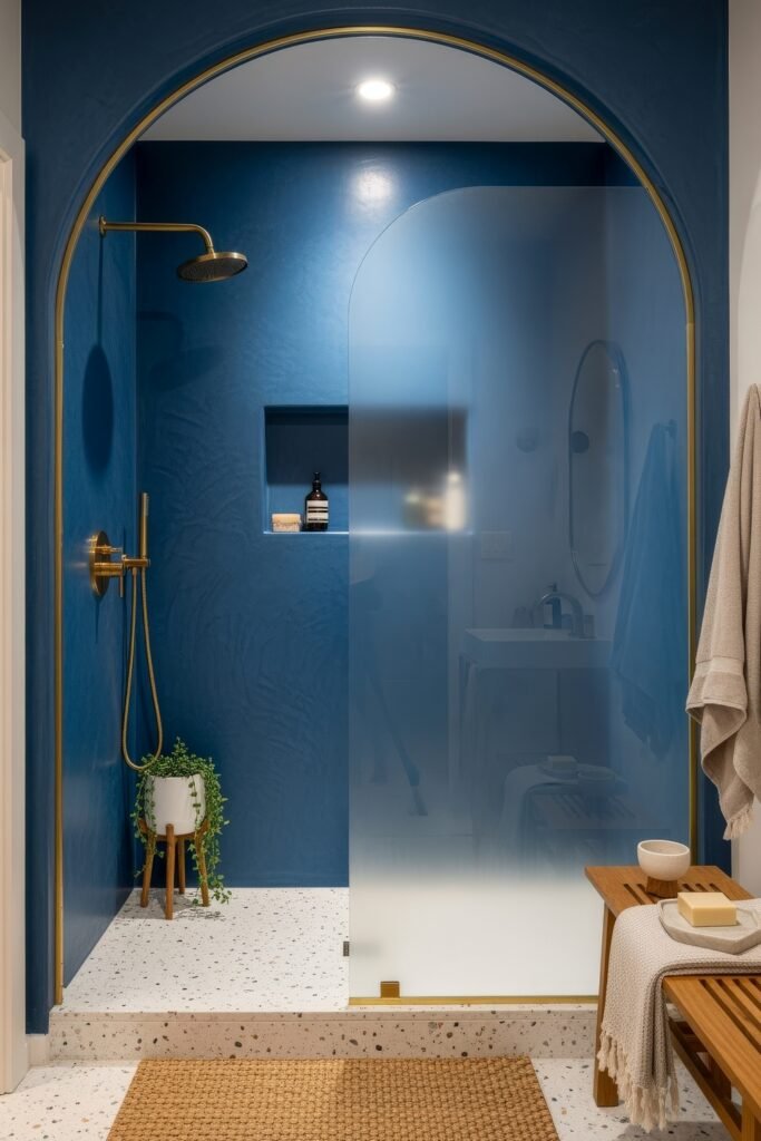 Blue Bathroom Decor: Fresh, Wow-Worthy Ideas 8 Sleek bathroom with arched frosted glass shower, deep blue walls, and brass fixtures paired with natural textures.