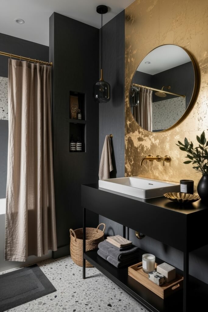 Black and Gold Bathroom Decor Ideas for Luxe Everyday Calm 14 Bathroom with a striking gold accent wall, black vanity with open shelving, terrazzo floors, and round mirror, styled with candles and greenery.