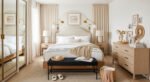 Bright neutral bedroom with a curved headboard, layered white bedding, light wood furniture, and cozy accents, offering elegant bedroom ideas for small rooms.