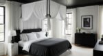Modern bedroom with a black canopy bed dressed in white and charcoal bedding, framed by sheer drapes, black furniture, and a minimalist black-and-white artwork.