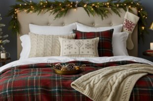 Bed styled with red and green plaid christmas bedding, knit throw blanket, and festive pillows, with garland, stocking, and candles creating cozy Christmas décor.