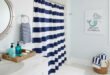 Nautical bathroom decor with navy and white striped shower curtain, wicker baskets, and a mermaid wall art for a touch of funny bathroom decor.