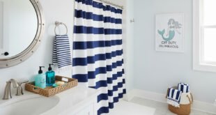 Nautical bathroom decor with navy and white striped shower curtain, wicker baskets, and a mermaid wall art for a touch of funny bathroom decor.