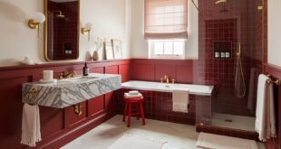 Elegant bathroom with red tile walls, a marble floating sink, a soaking tub, and a glass shower, styled with gold fixtures and soft lighting.