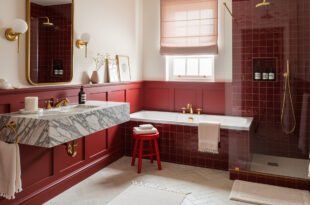Elegant bathroom with red tile walls, a marble floating sink, a soaking tub, and a glass shower, styled with gold fixtures and soft lighting.