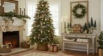 Cozy, Collected Magic With Vintage Christmas Decor Ideas Living room with a glowing fireplace, stockings, and a tall Christmas tree decorated with ornaments and silver garland beside a console table topped with a wreath and miniature holiday village, creating a cozy Christmas décor scene.