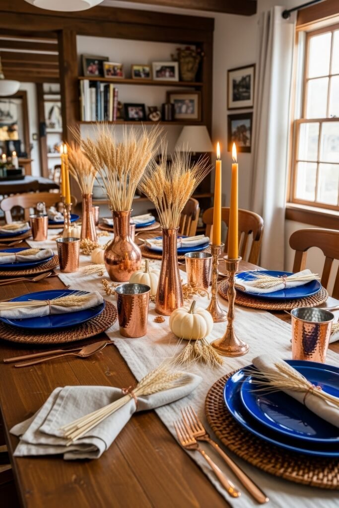 Fresh Ways to Style Blue Thanksgiving Table Décor 2 Rustic dining table with blue plates, copper cups, white pumpkins, and wheat-filled vases surrounded by warm candlelight.