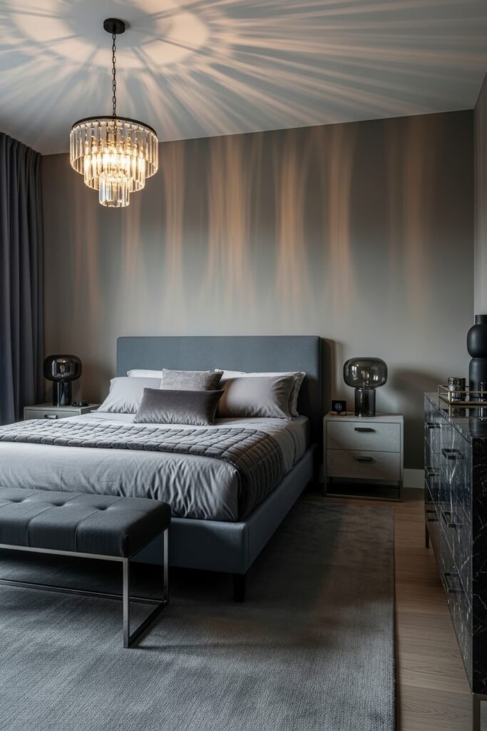 Grey bedroom ideas for a calm, stylish retreat 20 Elegant bedroom in layered shades of grey with a modern chandelier, tufted bench, black marble dresser, and subtle lighting effects.