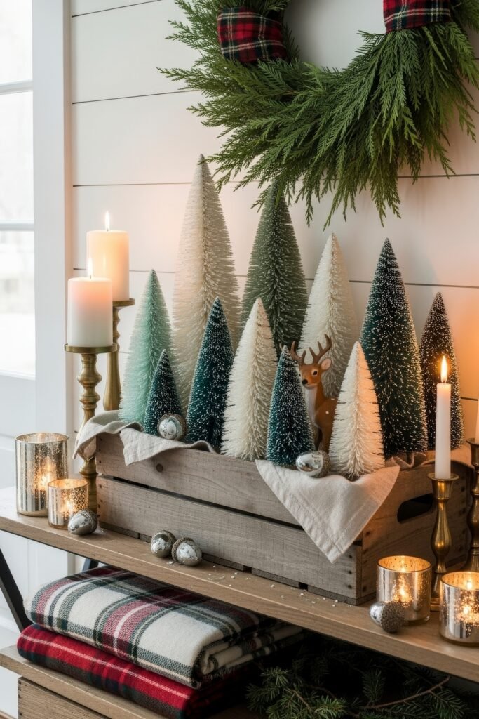Cozy Ways to Style Farmhouse Christmas Décor 19 Wooden crate filled with bottle brush trees, candles, and silver ornaments beneath a plaid-accented wreath, surrounded by cozy Christmas accents.