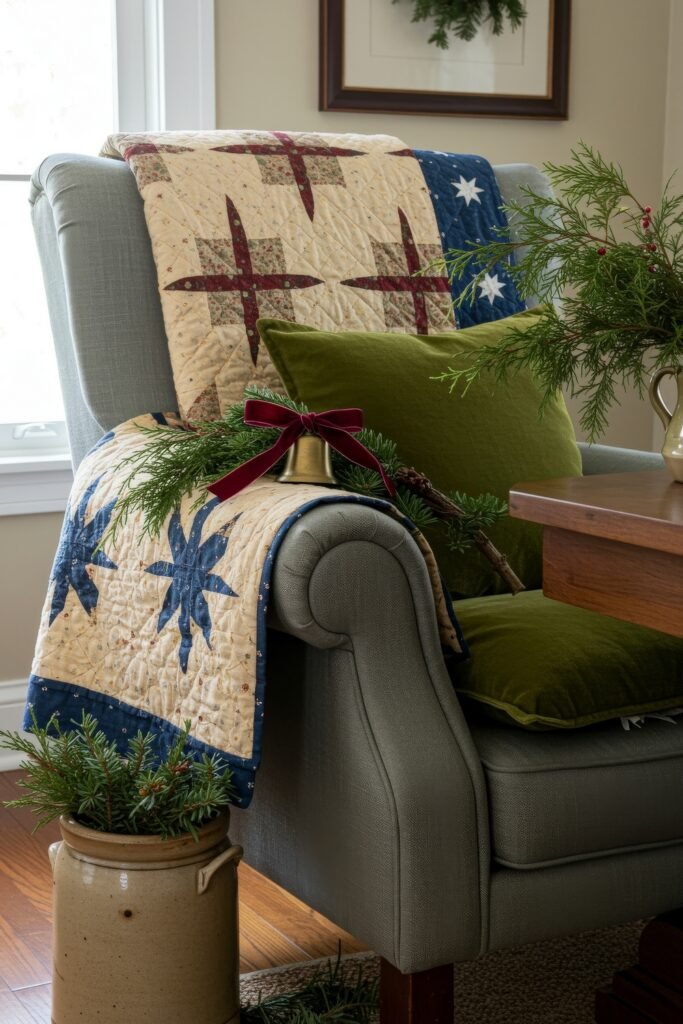 Cozy, Collected Magic With Vintage Christmas Decor Ideas 24 Armchair with a green velvet pillow and quilt in red, cream, and navy star patterns, accented with greenery and a velvet ribbon bell for a vintage Christmas décor touch.