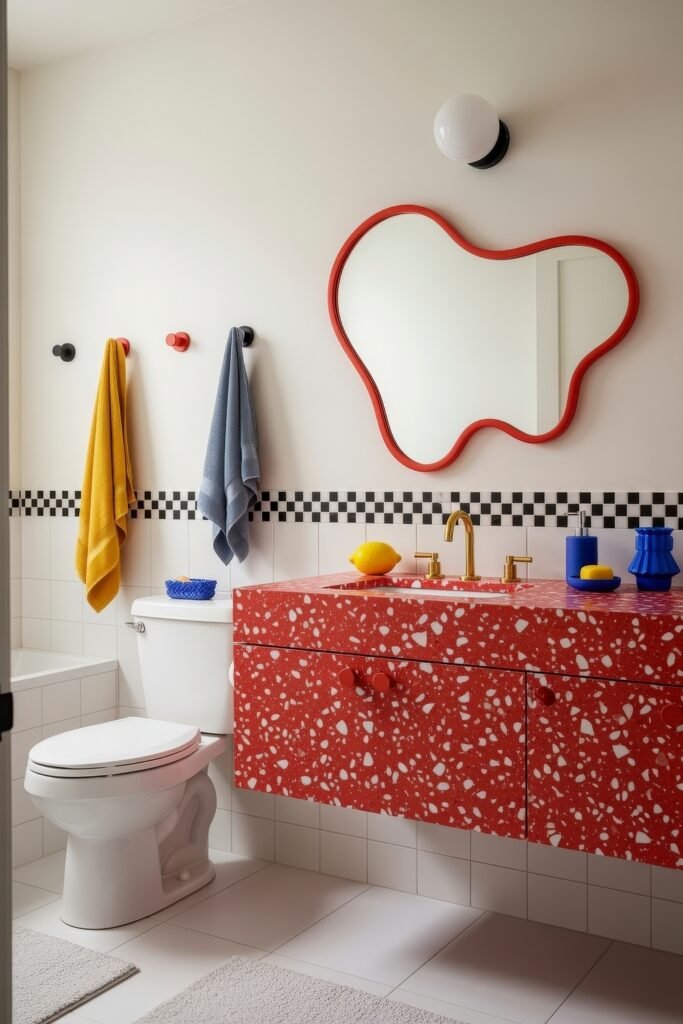 13 Bold Ideas for Red Bathroom Decor That Wow 12 Modern bathroom featuring a red terrazzo vanity with gold faucet, wavy red-framed mirror, and bright towels in yellow and blue for vibrant bathroom decor.