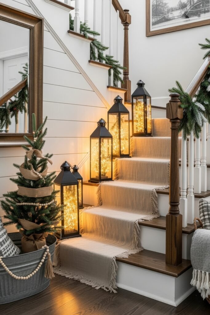 Cozy Ways to Style Farmhouse Christmas Décor 13 Staircase lined with glowing lanterns, greenery garland, and a small Christmas tree wrapped in burlap and beads for a farmhouse Christmas décor touch.
