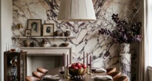 Elegant dining room with a round wood table and leather chairs beneath a large pendant against a dramatic bookmatched marble wall
