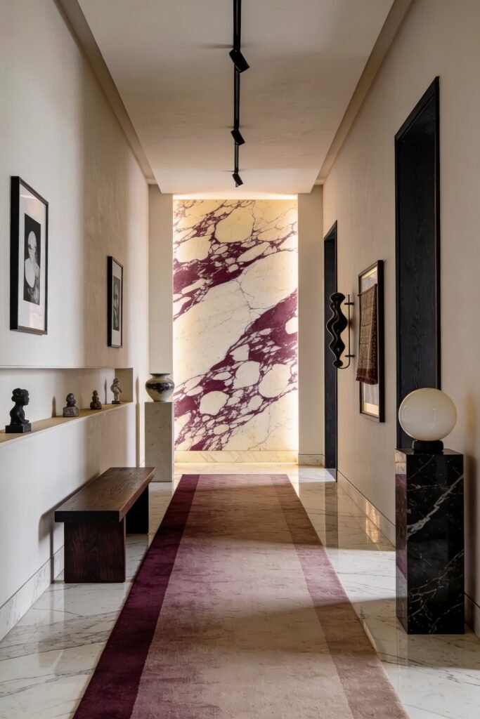 Long hallway with framed art a wood bench and a glowing purple veined marble panel at the far end
