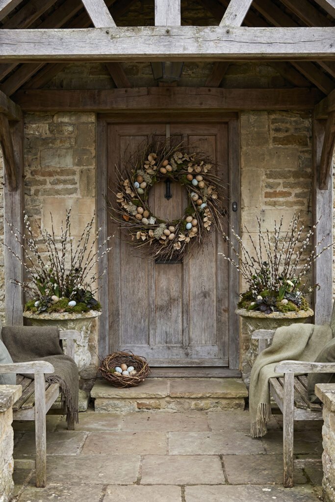Easter Front Porch Ideas for a Fresh Spring Entry 31 Rustic stone porch with a weathered wood door egg wreath pussy willow urns and a nest of pastel eggs