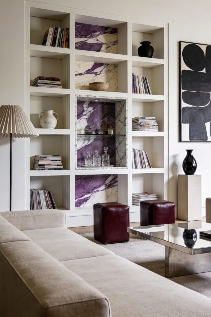 Bright living room with a grid bookcase displaying books and glassware against purple veined marble panels