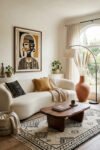 Curved cream sofa with ochre pillows, abstract portrait wall art, terracotta floor vase, arc lamp, and geometric rug in a warm Afro Boho Decor living room.